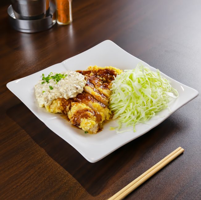 甘酢だれとタルタルソースをかけた鶏の揚げものと千切りキャベツ