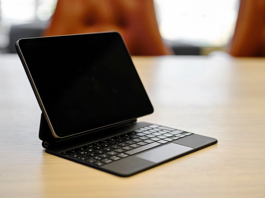 木のテーブルに置かれたキーボードケース付きのタブレット