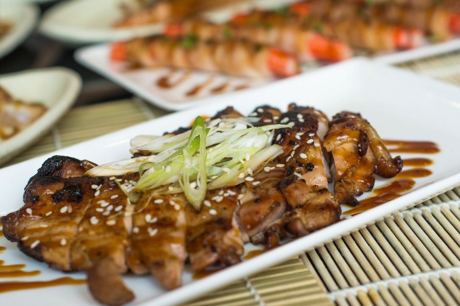 白い皿に盛った鶏の照り焼き。白髪ねぎとごまをのせ、甘辛いたれで照りが出ている