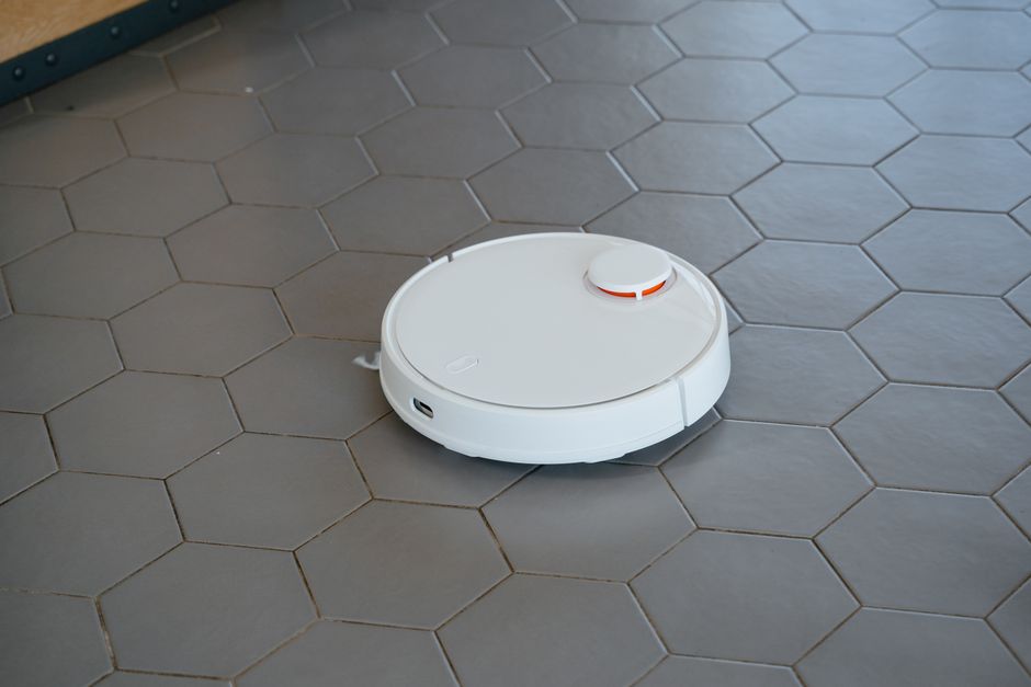 タイル床の上を走る白い円形のロボット掃除機