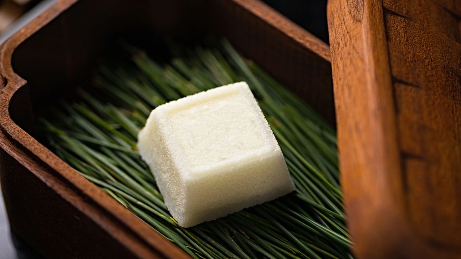 木箱の葉の上に置かれた、四角く切った白い和菓子